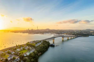 Auckland, with the Sky Tower and CBD visible across Waitemata Harbor and the Auckland Harbour Bridge